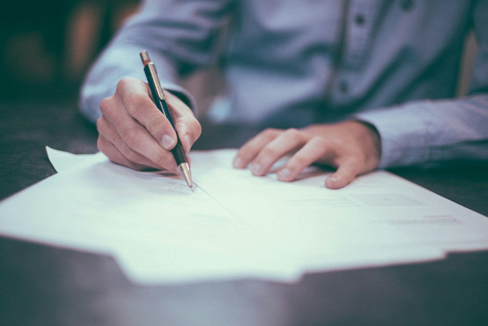A fountain pen poised over a confidential settlement document