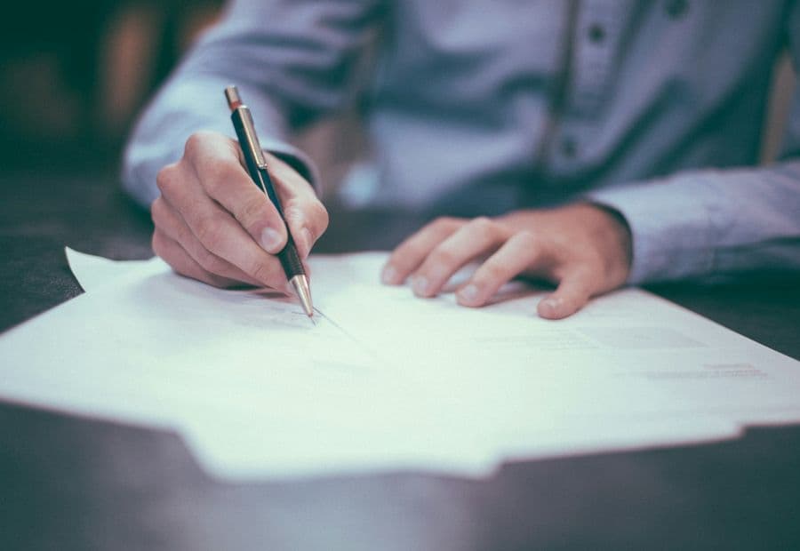 A fountain pen poised over a confidential settlement document