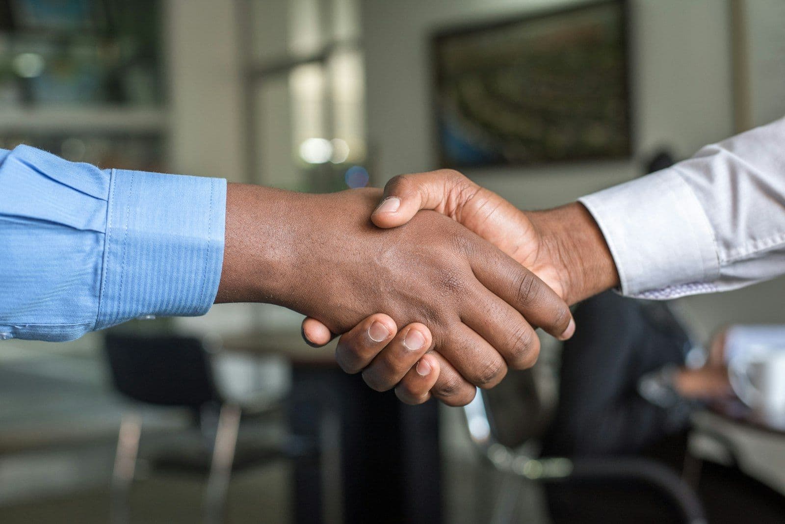 Two parties shaking hands across a table after reaching agreement